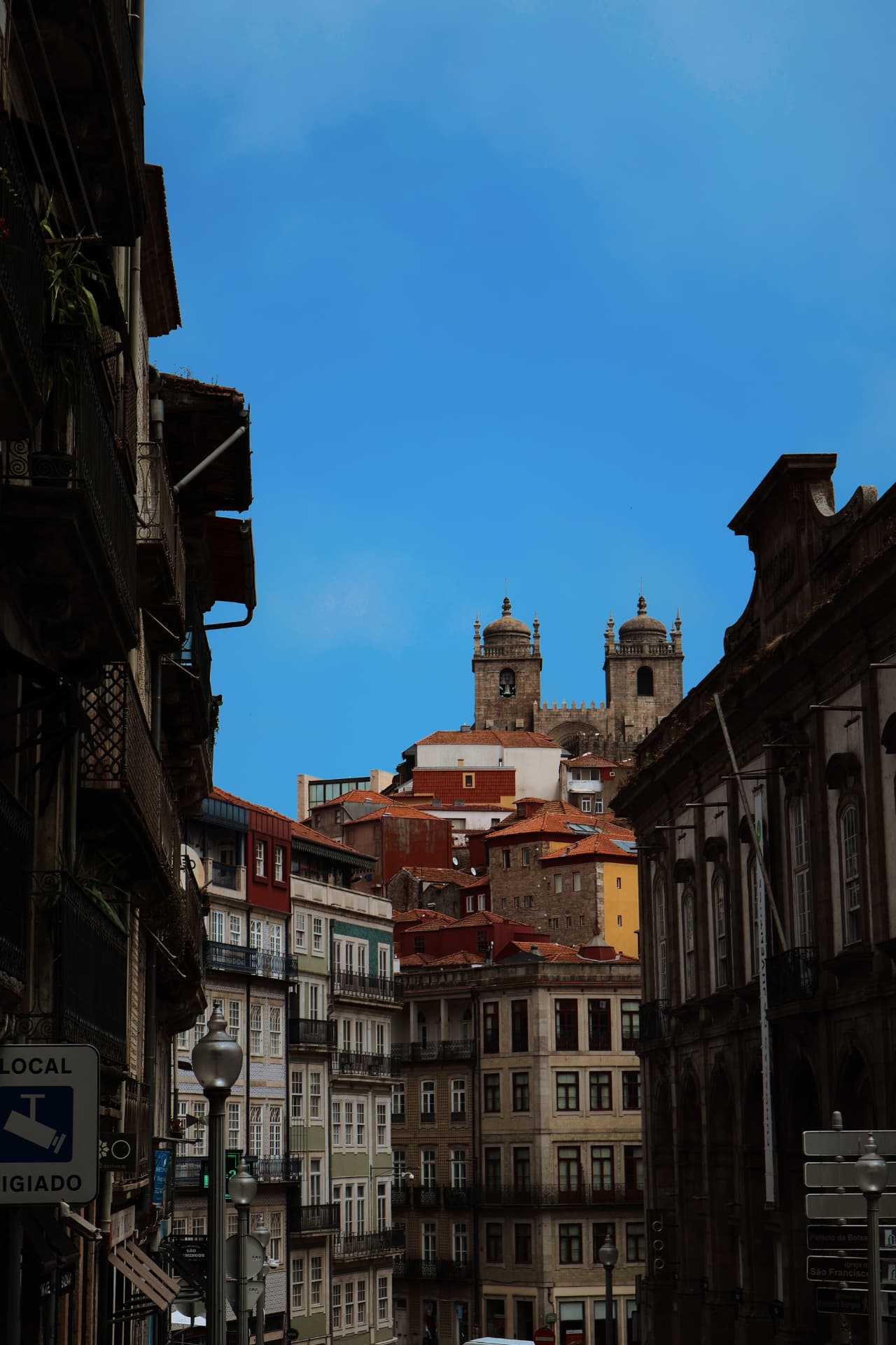 A steep street of tiled facades rising toward twin cathedral towers against a clear sky